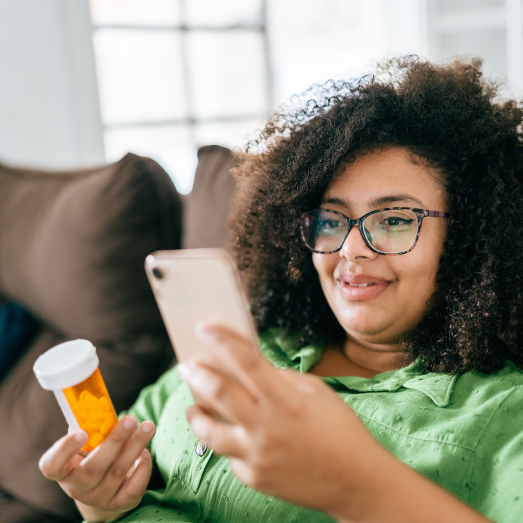 Woman smiling and holding medication on telehealth call
